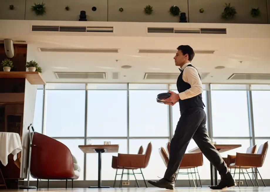 Waiter serving in a modern dining room supported by fast TableQR digital menus for peak hours